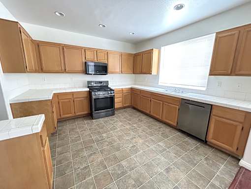 A kitchen with brown cabinets and a black stove top oven.