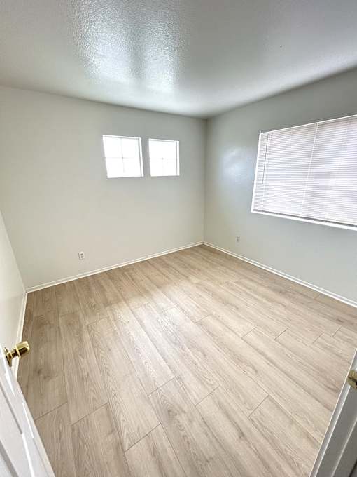 A room with a wooden floor and a window with blinds.