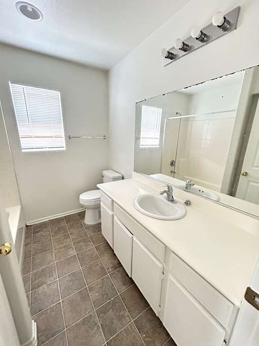 A bathroom with a toilet, sink, and mirror.