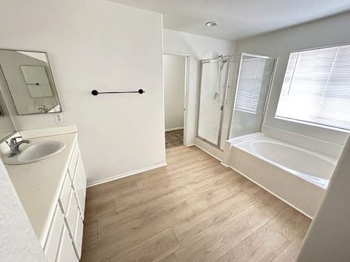 A white bathroom with a sink, mirror, and bathtub.