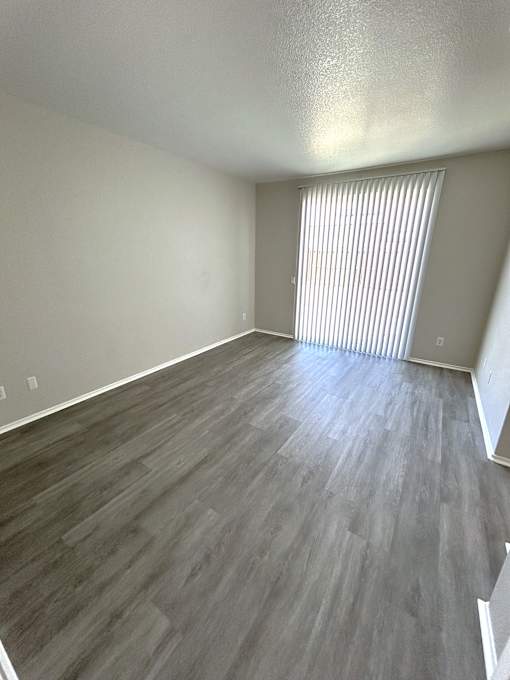 A room with wooden flooring and a window with blinds.