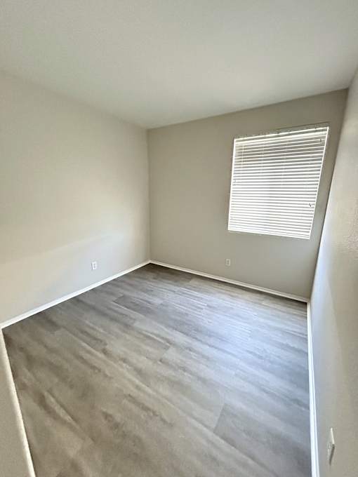 A room with a window and wooden flooring.