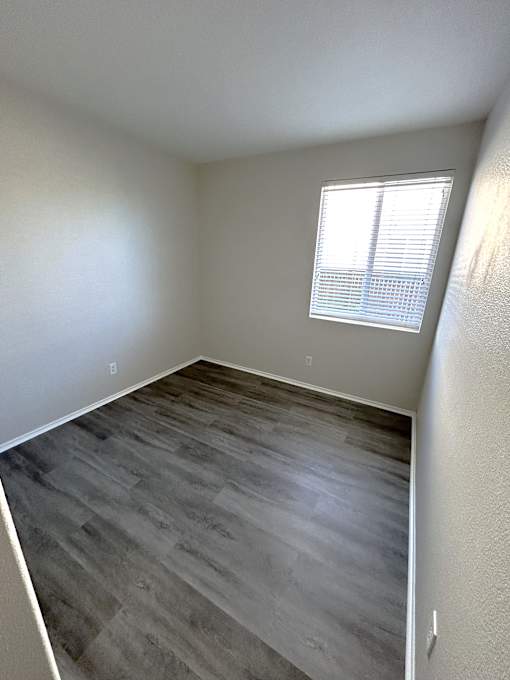 A room with a window and wooden flooring.