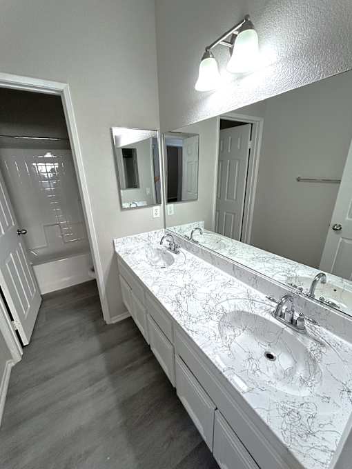 A bathroom with a marble countertop and a large mirror.