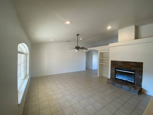A living room with a fireplace and a ceiling fan.