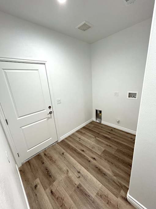 A room with a white door and wooden flooring.