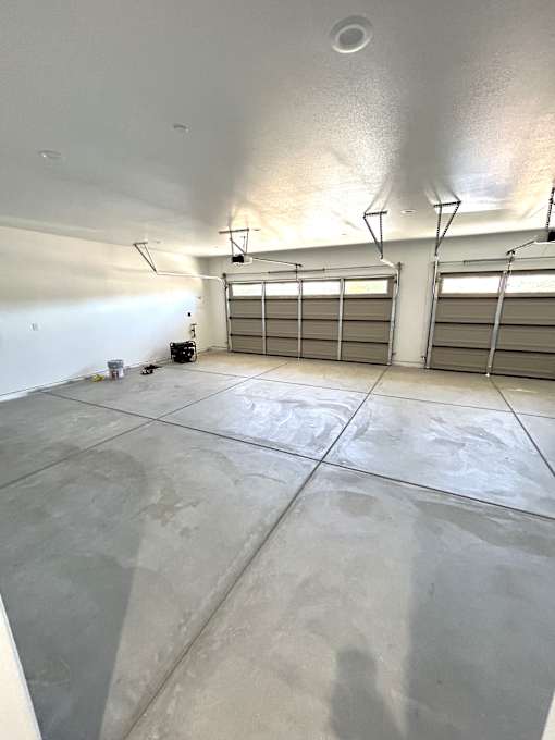 A garage with a concrete floor and two overhead lights.