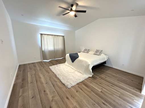 A bedroom with a bed and a ceiling fan.