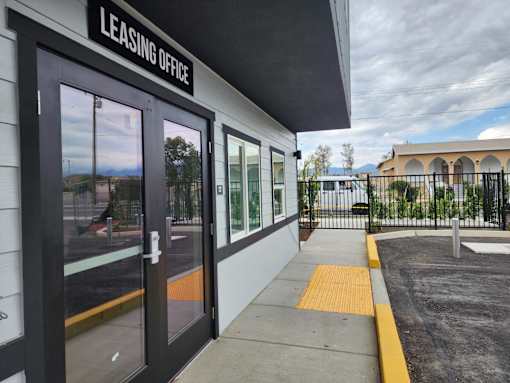 The image shows the front of a leasing office with a sign above the door.