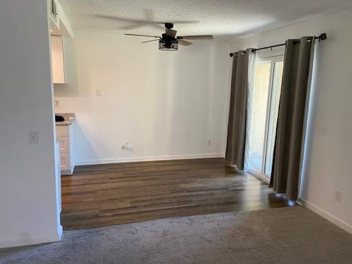 A room with a ceiling fan and sliding glass doors.