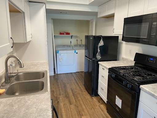 A kitchen with a black stove top oven and a black microwave above it.