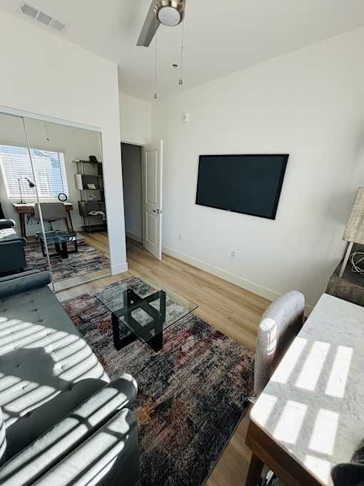 A living room with a black flat screen TV mounted on the wall.