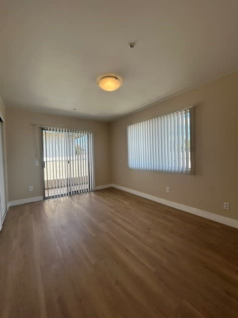 A room with wooden floors and a window with blinds.
