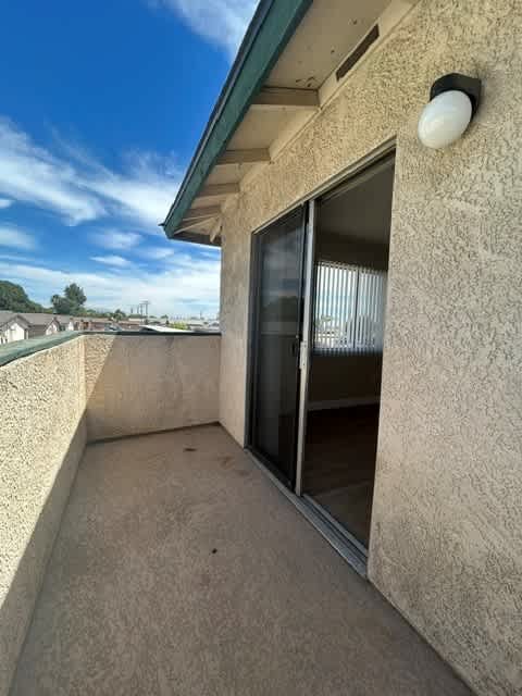 A balcony with a sliding glass door and a wall lamp.