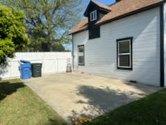a backyard patio with a white house and a white fence