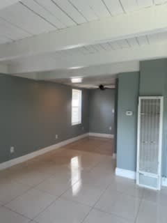 an empty living room with a white tile floor and green walls