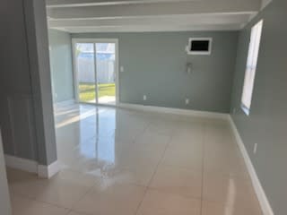 an empty living room with a tile floor and a door to a balcony
