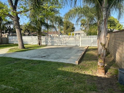a sidewalk in a yard next to a white fence