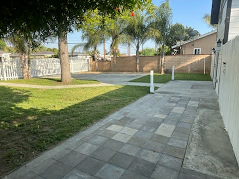 a sidewalk in front of a house with a fence