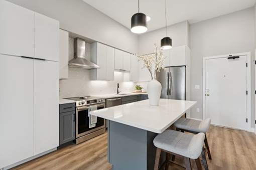 A modern kitchen with a white countertop and grey cabinets.