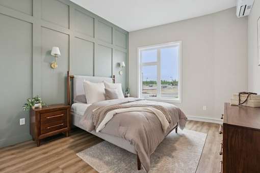 A bedroom with a large bed and a window overlooking the beach.
