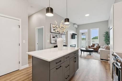 A modern kitchen with a white island and wooden floors.