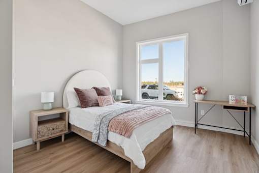 A bedroom with a large bed and a window overlooking a parking lot.