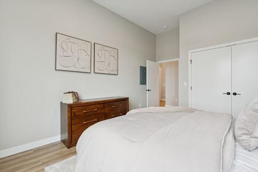 A bedroom with a bed, dresser, and two framed pictures on the wall.