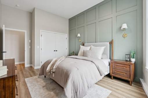 A bedroom with a bed, nightstand, and two wall lamps.