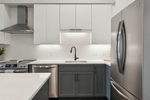 A modern kitchen with a stainless steel refrigerator and a white countertop.