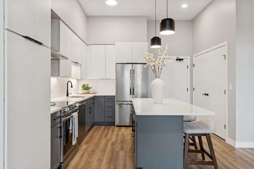 A modern kitchen with a white countertop and stainless steel appliances.
