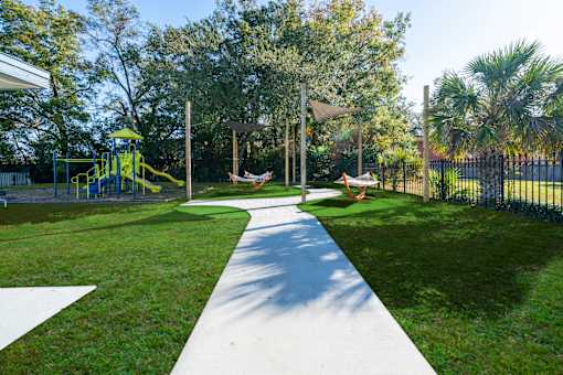 A playground with a yellow slide and a white pathway. at Red Bay Apartment Complex, Jacksonville, FL, 32211