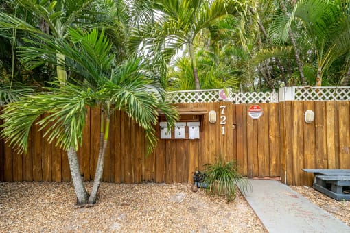 a wooden fence with a do not enter sign and a palm tree in front of it