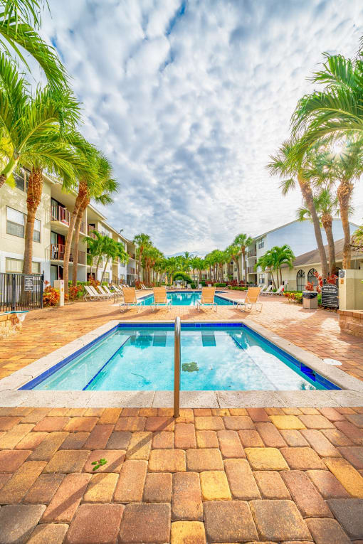 a resort style pool with palm trees and buildings in the background