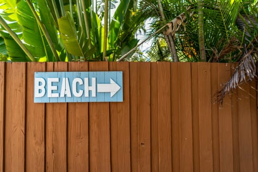a sign that says beach on a wooden fence