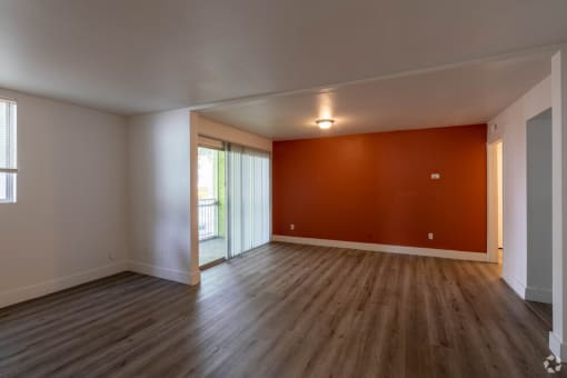 an empty living room with a red accent wall at Red Bay Apartment Complex, Jacksonville