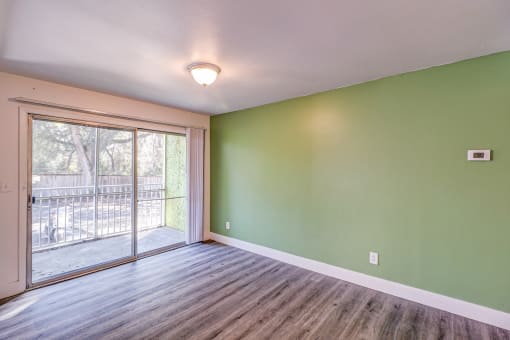 a living room with green walls and a sliding glass door to a balcony at Red Bay Apartment Complex, Jacksonville, FL, 32211