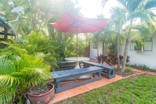a picnic table with a red umbrella in a backyard