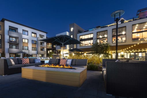 a patio with a fire pit and seating in front of a building
