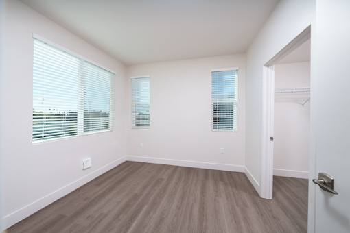 an empty room with white walls and wood flooring and windows