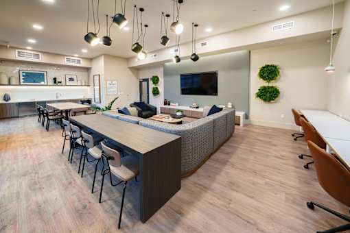 a communal area with a long table and chairs and a kitchen with a television