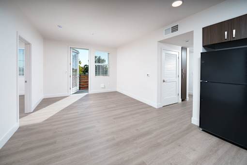 a living room with white walls and a black refrigerator