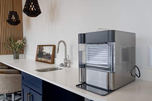 A modern kitchen with a sink, faucet, and a coffee maker.