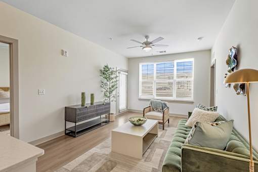 A living room with a green couch, a wooden coffee table, and a ceiling fan.