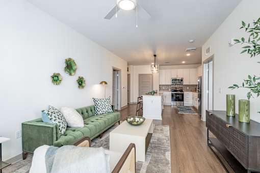 A living room with a green couch and a white ceiling fan.