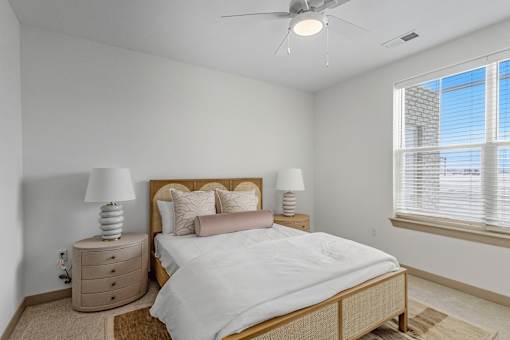 A bedroom with a bed, nightstands, and a window.