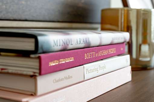 A stack of books with titles such as "Minol Araki" and "Picturing People" are displayed.