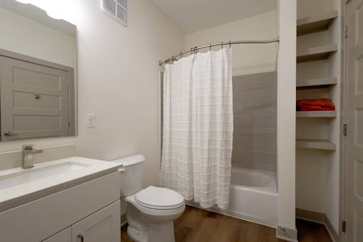 A white bathroom with a toilet, sink, and shower.