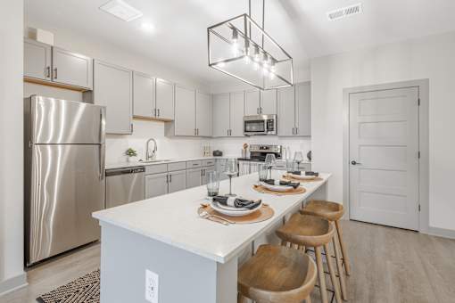 A modern kitchen with a white countertop and stainless steel appliances.