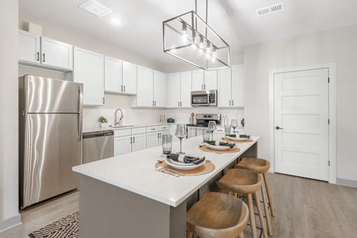 A modern kitchen with a white countertop and stainless steel appliances.